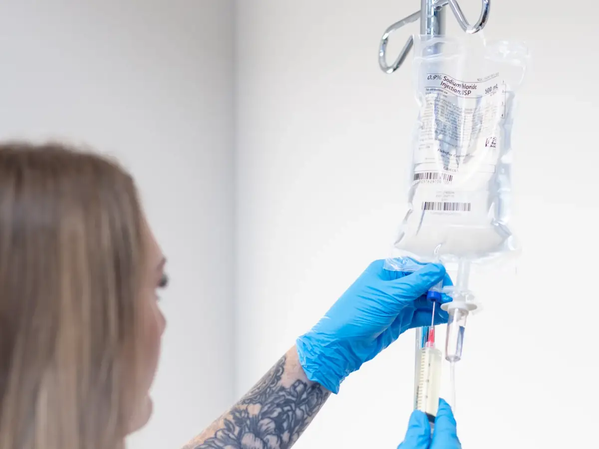 A gloved Pura Vida clinician setting up an IV drip line in Fleming Island, FL