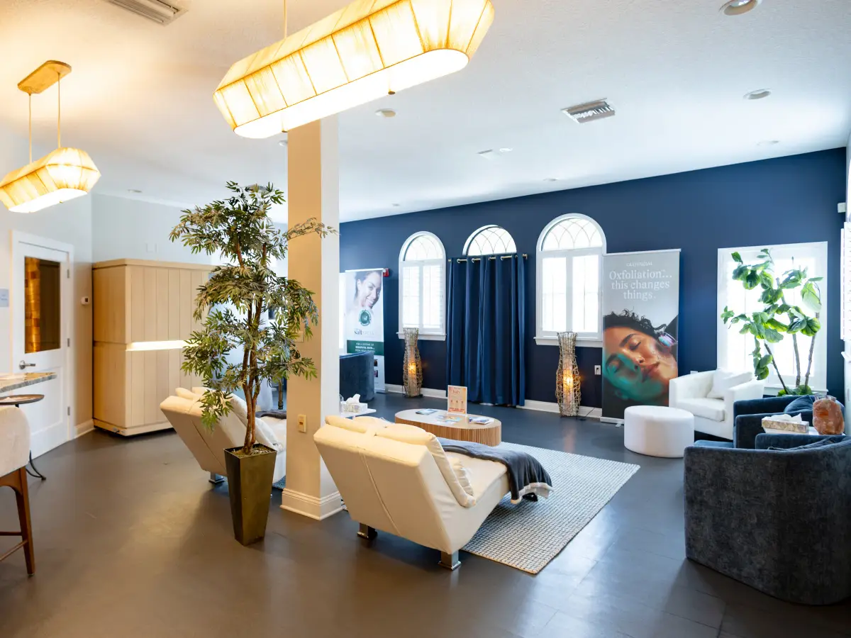 The relaxation lounge at the Pura Vida Day Spa in Fleming Island, FL, with cream recliners, a Himalayan salt lamp, and the infrared sauna included in the Deluxe Spa Day Package