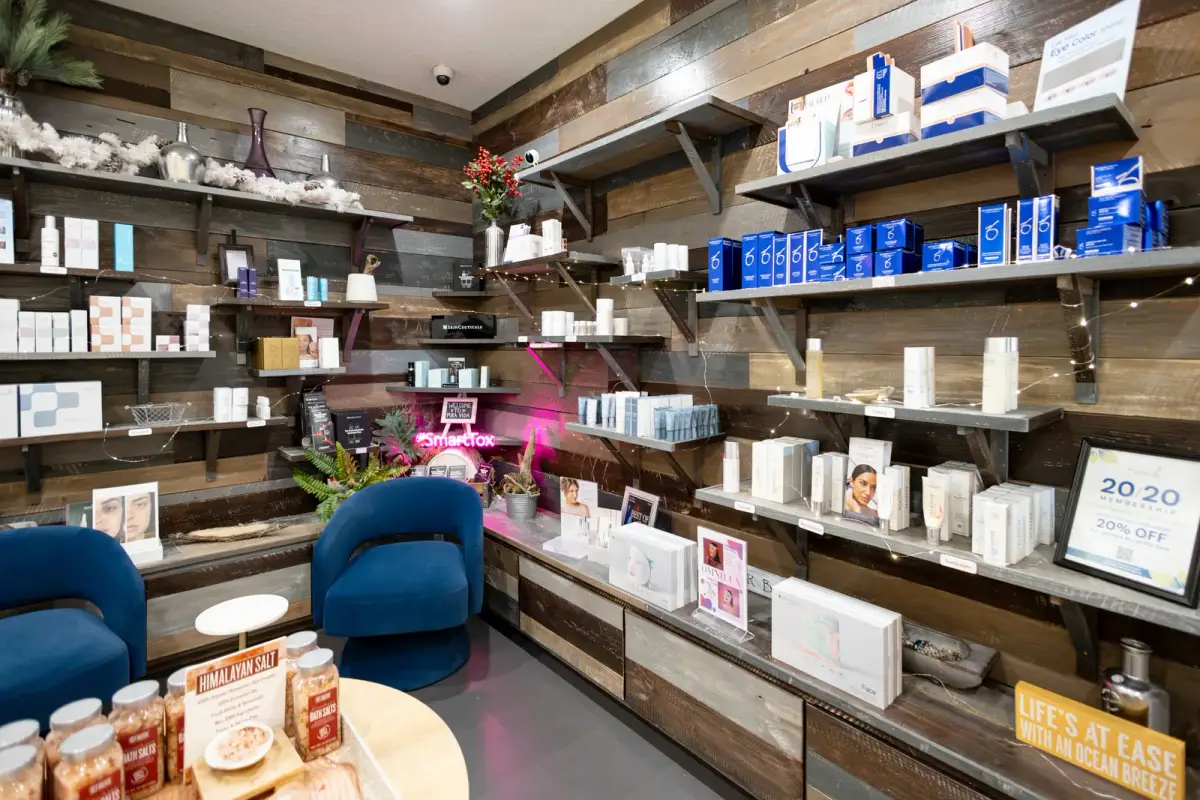 The Pura Vida skincare boutique in Fleming Island, FL, with medical-grade products on rustic wood shelves and blue lounge chairs