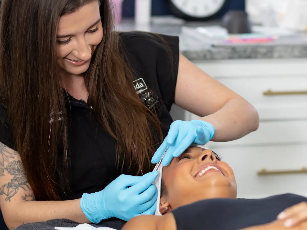 Macy Castello, medical aesthetician at Pura Vida, smiling as she treats a guest's skin during a facial in Fleming Island, FL